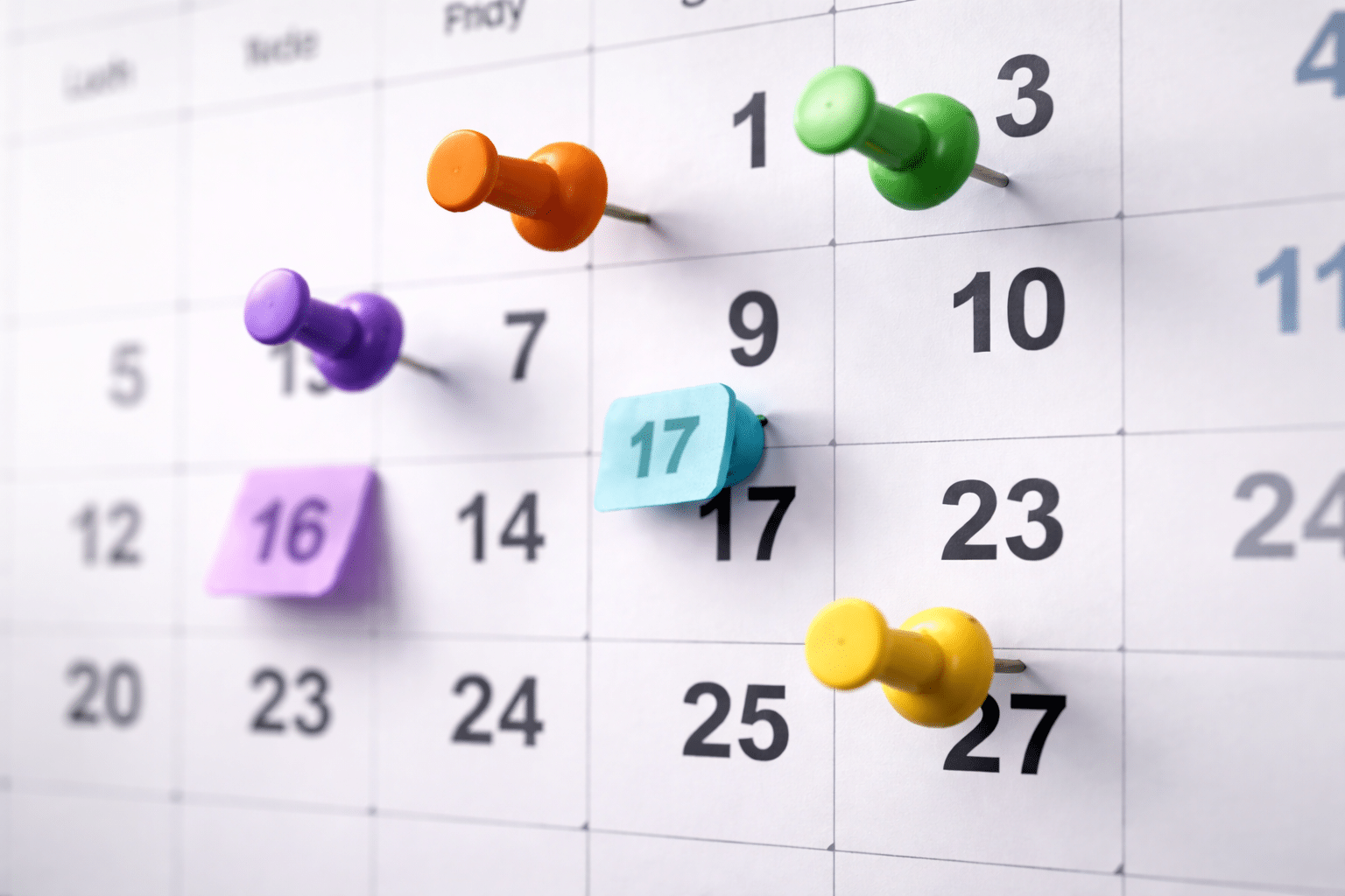 Calendrier mensuel avec punaises colorées pour planification et organisation des tâches