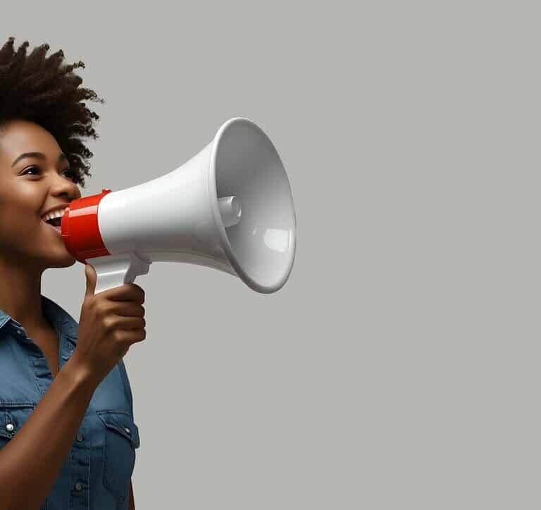 Jeune femme souriante parlant dans un mégaphone, métaphore de l'outbound marketing.