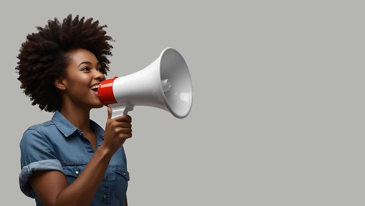 Jeune femme souriante parlant dans un mégaphone, métaphore de l'outbound marketing.